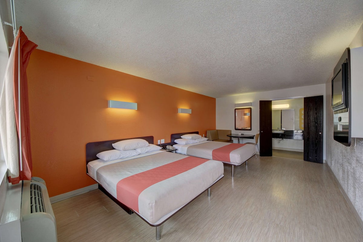 Une chambre d’hôtel avec deux lits, une salle de bain et un téléviseur.