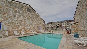Une piscine avec des chaises longues et un mur en pierre.