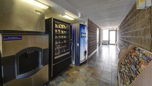 Un couloir avec des distributeurs automatiques, une bibliothèque et une porte donnant sur un autre espace.
