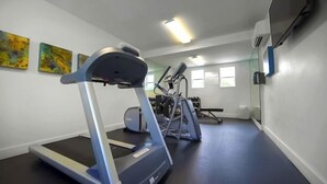 Une salle de sport équipée de tapis de course, d’appareils elliptiques et de vélos d’exercice.