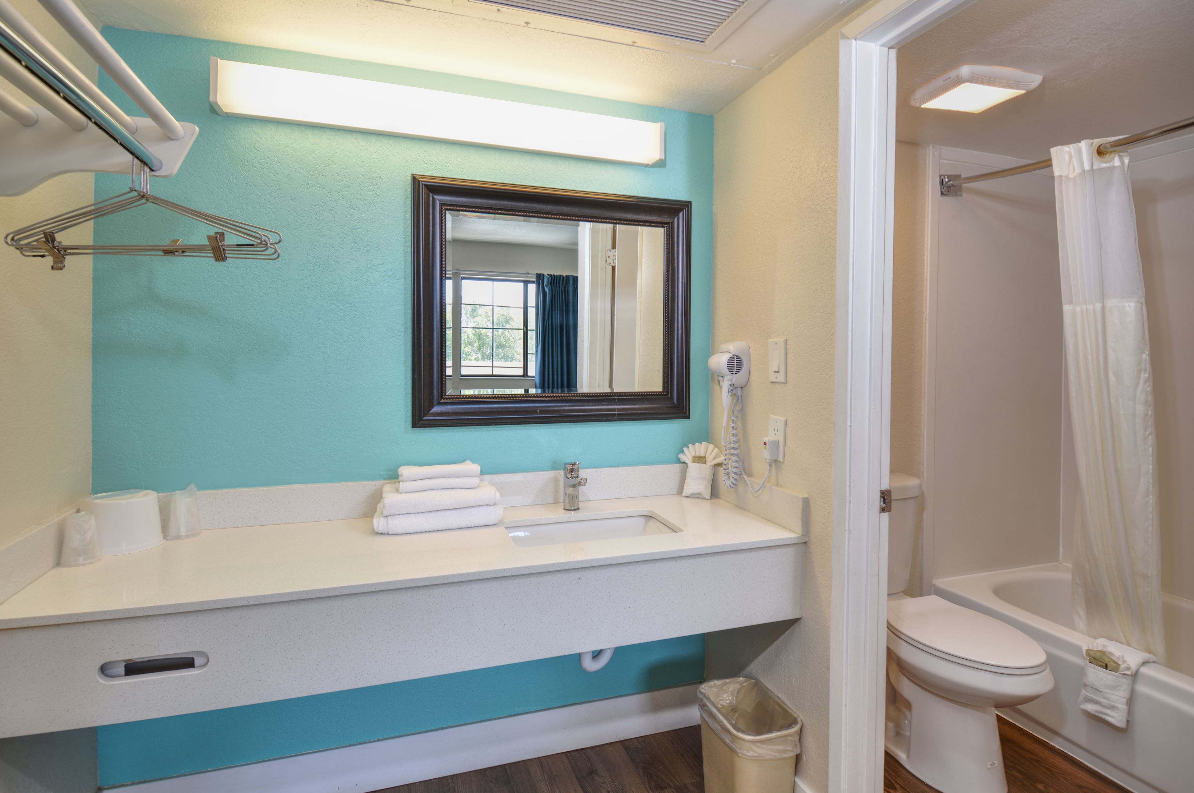 A bathroom with a sink, mirror, and shower.