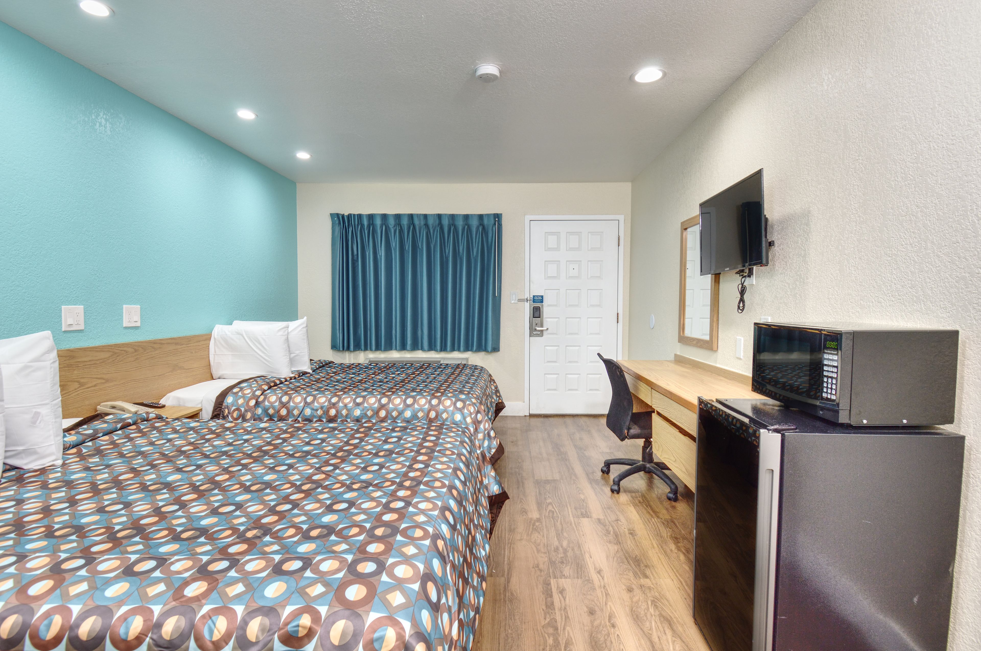 Habitación de hotel con dos camas, un escritorio, un microondas y una televisión.