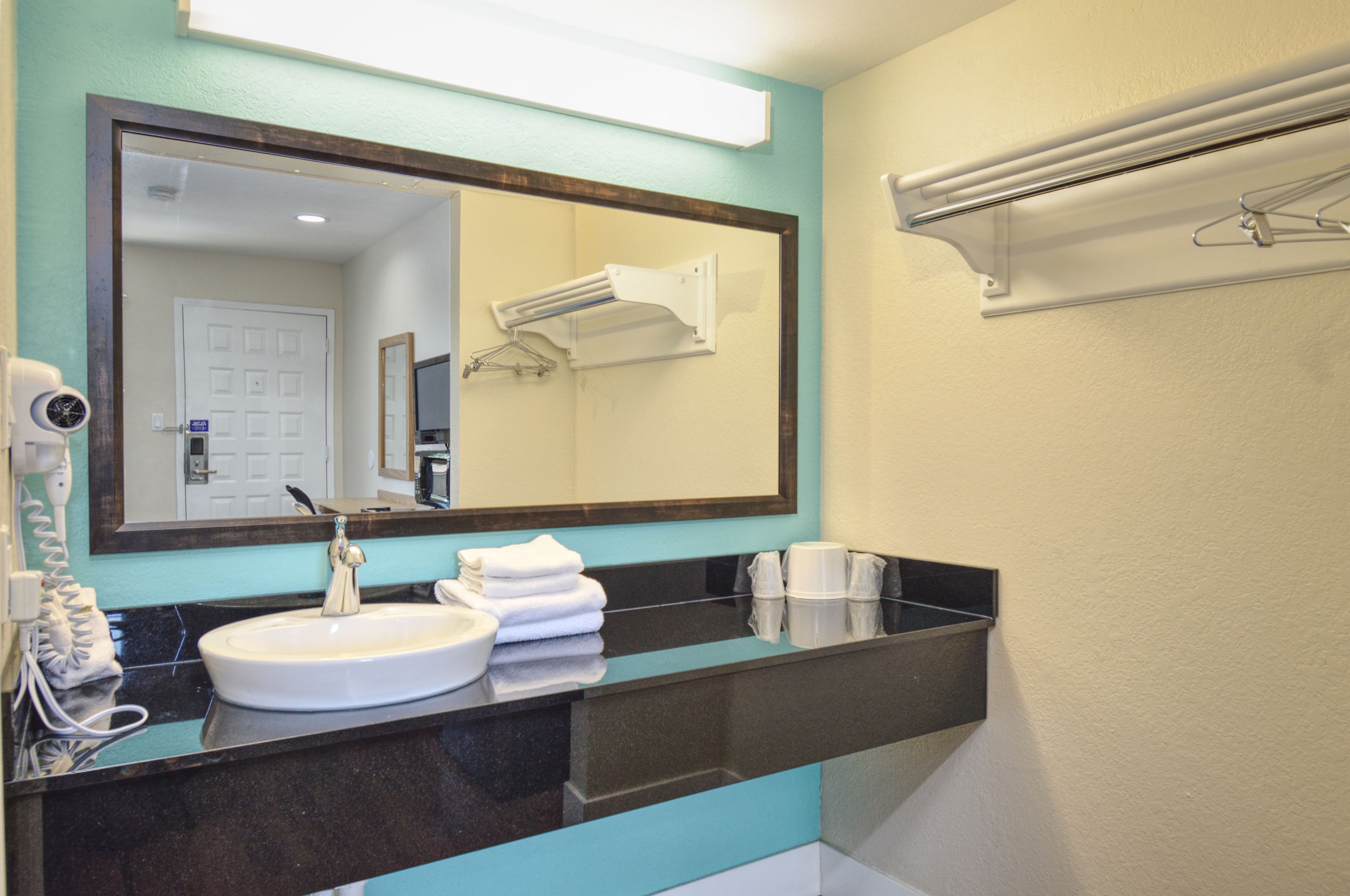 A bathroom with a sink, mirror, towel rack, and a hairdryer.