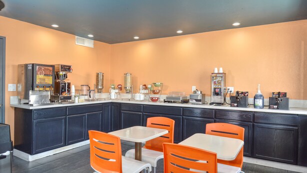 Un espace cuisine doté d’un îlot central, de chaises orange et d’une table blanche.