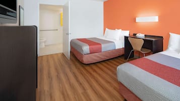 Habitación de hotel con dos camas, un escritorio y un baño.