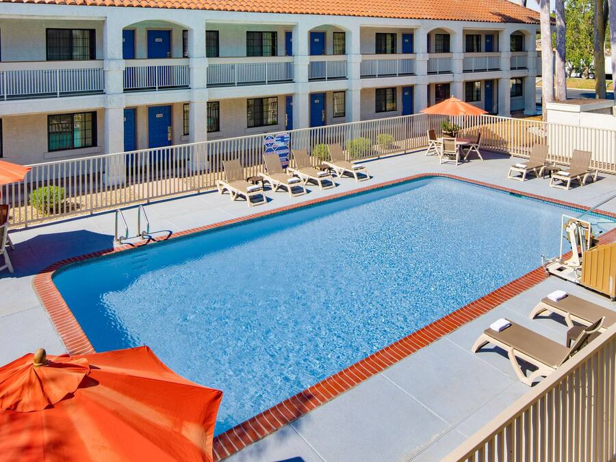 A hotel with a swimming pool, sun loungers, and umbrellas.