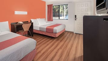 Habitación de hotel con dos camas, un escritorio, una silla, un televisor y una ventana con cortinas.