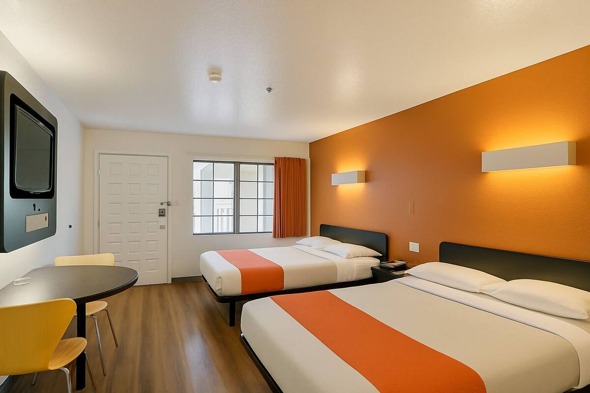 Une chambre d’hôtel avec deux lits, un bureau et une chaise.