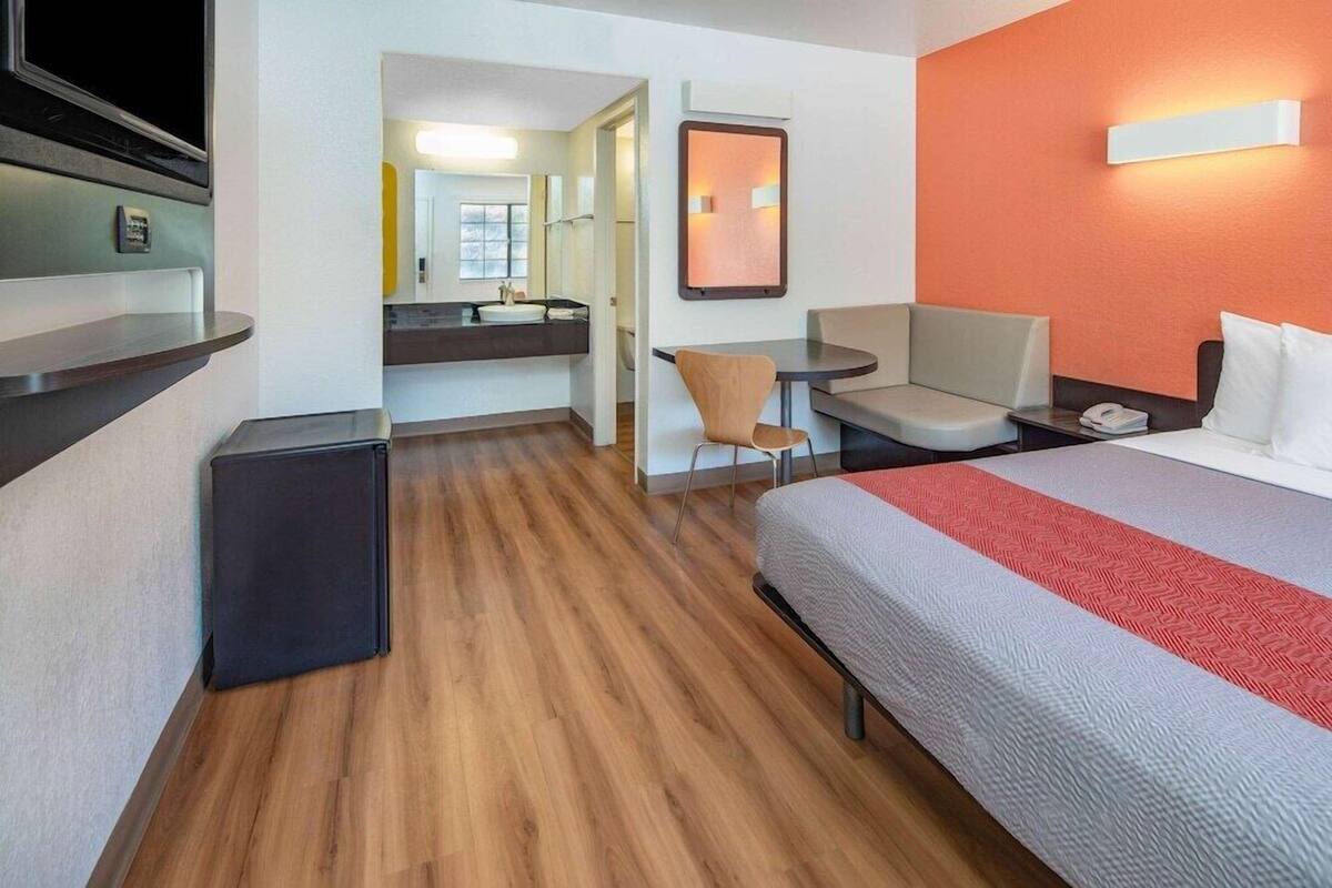 Une chambre d’hôtel comprenant un lit, un bureau, une chaise, une petite table, un miroir et un téléviseur.