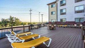 A deck with sun loungers and outdoor seating, overlooking a building with multiple windows.