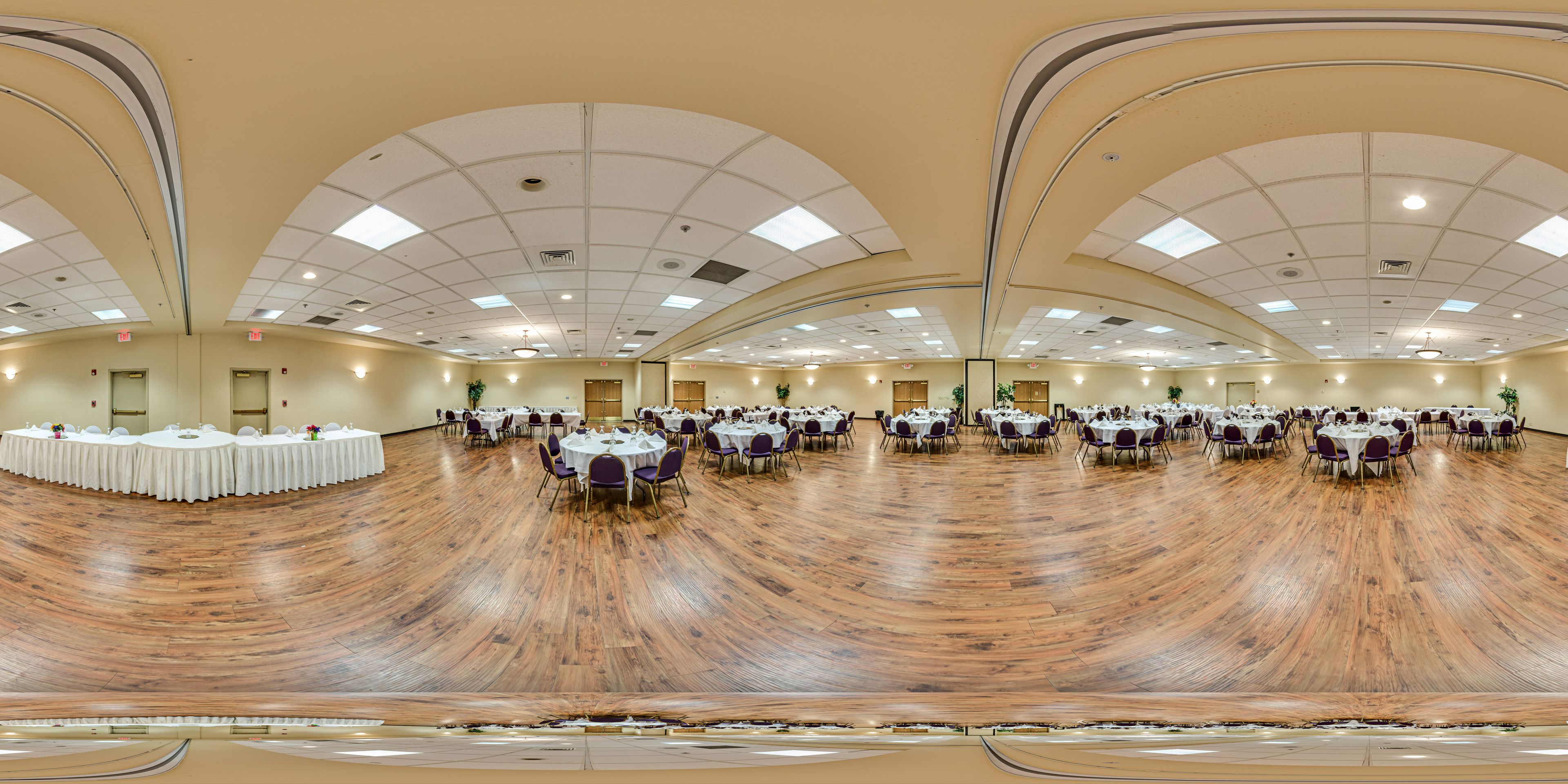 A large hall with multiple round tables and chairs, arranged in a semi-circular pattern.