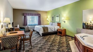 A hotel room with a bed, desk, chair, and a bathroom with a bathtub.