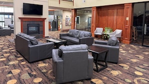 A lobby with leather sofas, a fireplace, a flat-screen TV, and a reception desk.