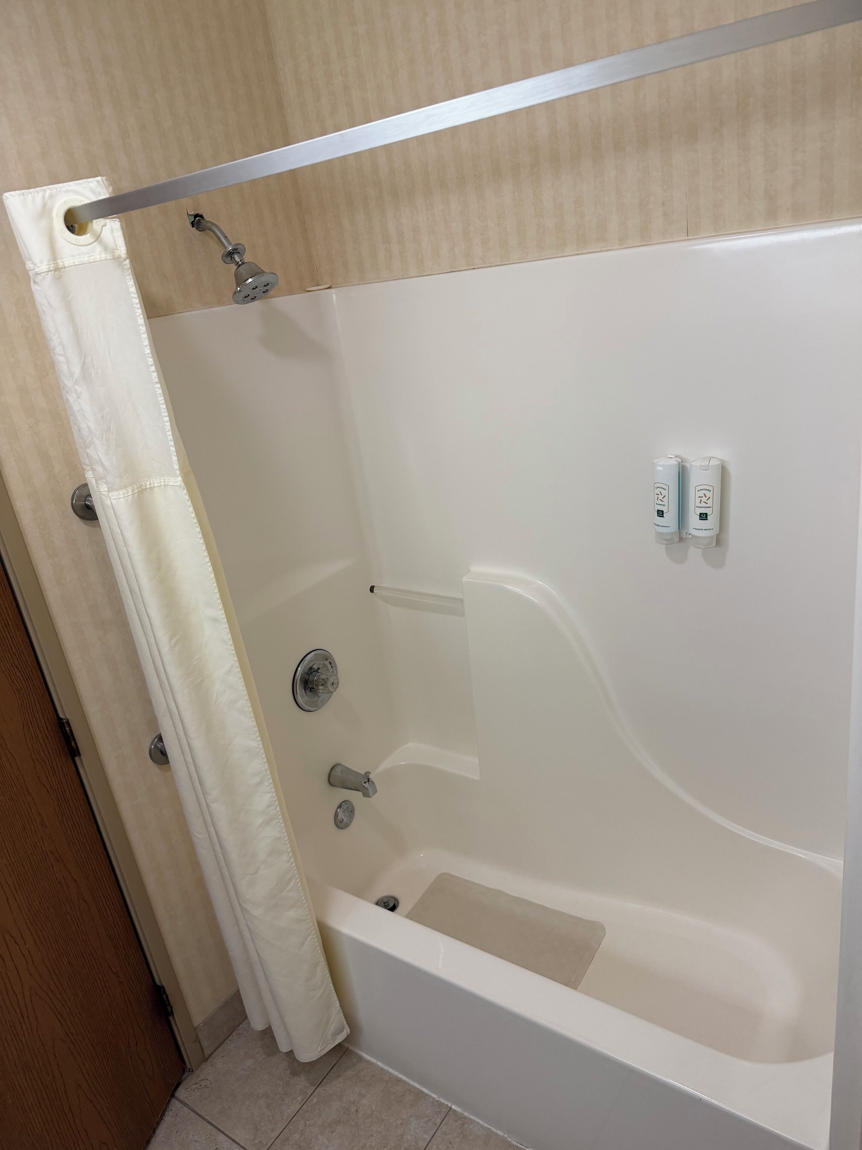 Una bañera con ducha, panel de control y cortina.