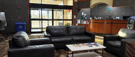 A lobby with leather sofas, a reception desk, and a blue trash bin.