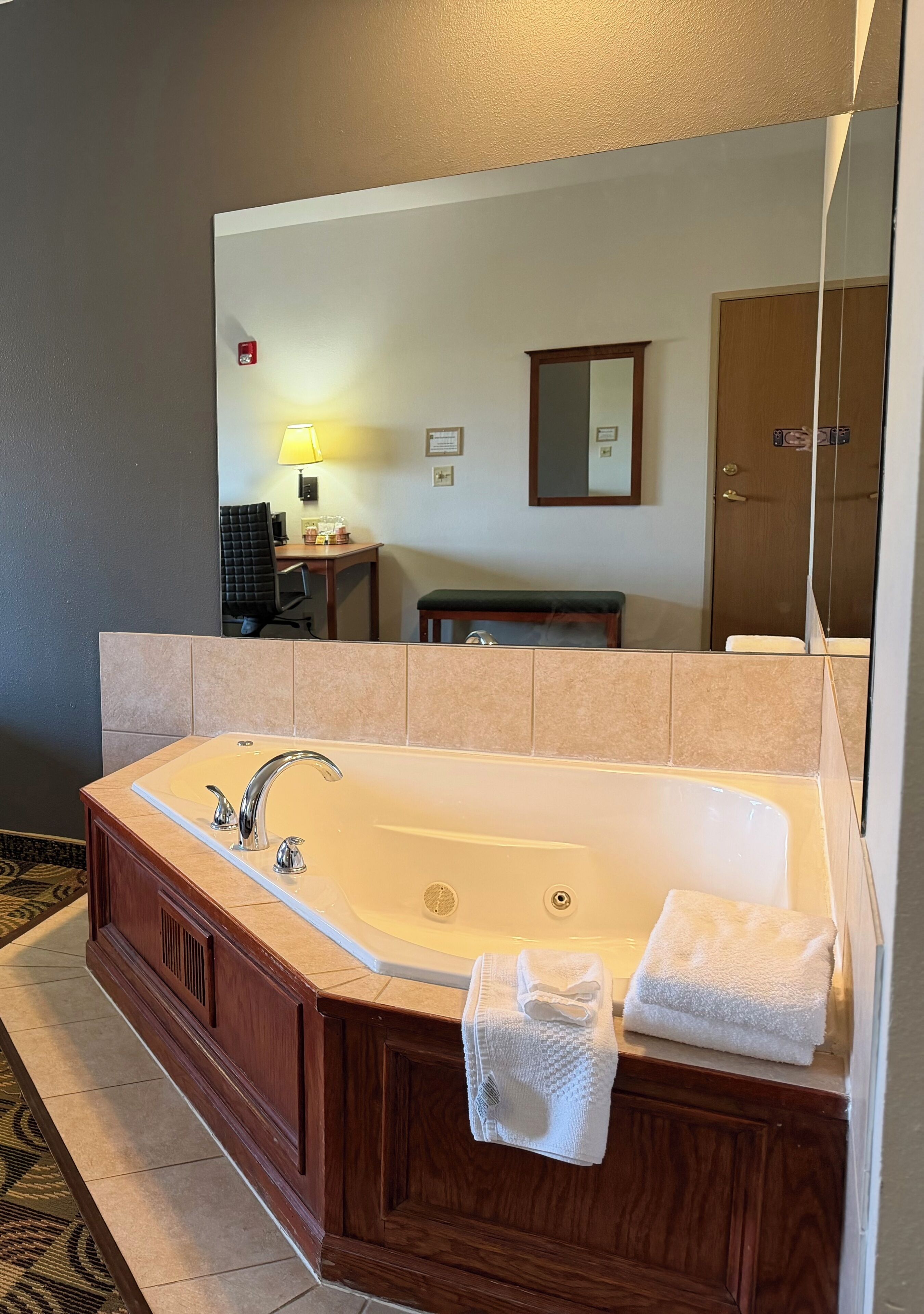 Un baño de hotel con una bañera grande, un espejo y un perchero para toallas.