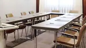 A conference room with a long table, chairs, and a window with curtains. - Hotel Ciutat Martorell (Martorell)