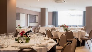 A dining area with multiple round tables set for a meal, each with white tablecloths, chairs, and glassware. - Hotel Ciutat Martorell (Martorell)