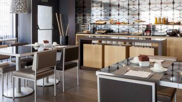 Un restaurante moderno con un diseño limpio y minimalista, que incluye una zona de buffet con diversas opciones de comida y un área de estar con mesas y sillas.