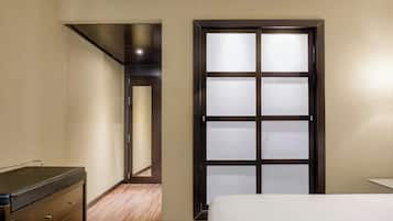 Una habitación de hotel con una cama, un aparador y un armario con paneles de vidrio esmerilado.