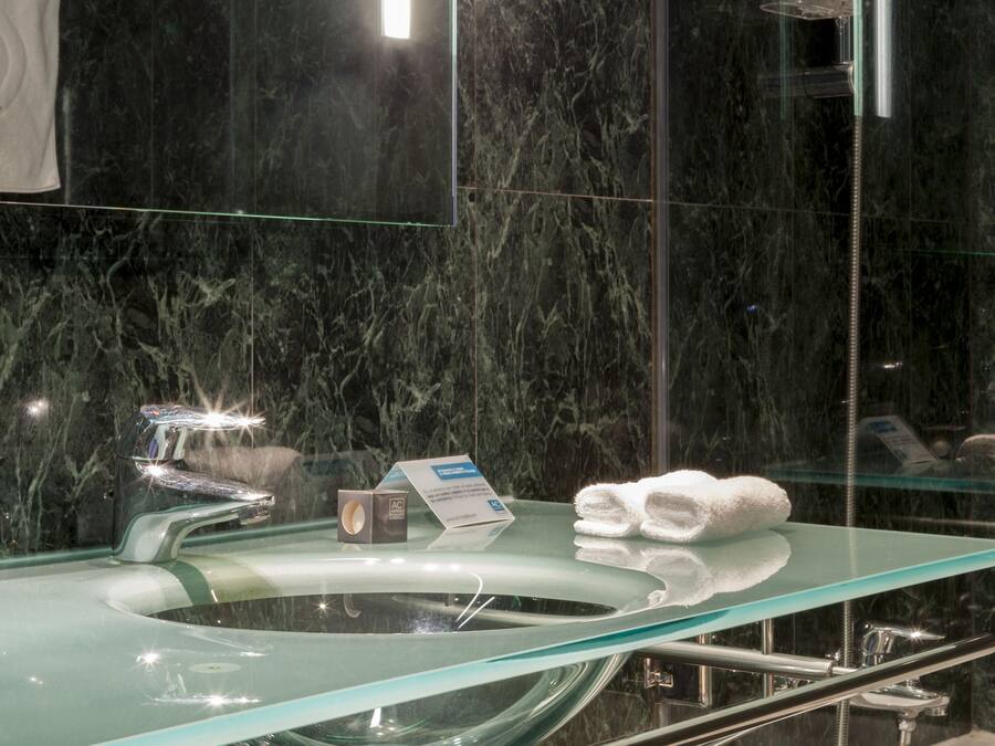 Un baño moderno con un lavabo de vidrio, un perchero y un espejo.