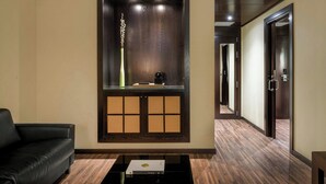 A modern hotel lobby with a dark wood reception desk, a black leather sofa, and a wooden floor. - AC Hotel Elda by Marriott (Elda)