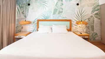 A bedroom with a large bed, two bedside tables, and a wall with a tropical leaf pattern.