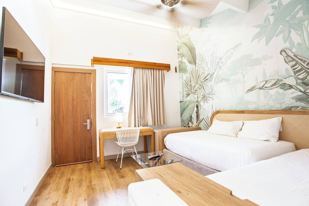 Una habitación de hotel con un escritorio de madera, una cama y un ventanal con cortinas.