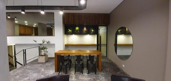 A modern kitchen with a wooden table and chairs, a tiled backsplash, and a round mirror on the wall.