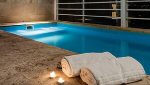 A swimming pool with two towels and two lit candles on the edge. - Hotel Mendoza (Mendoza)