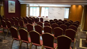 Un salón de conferencias con filas de sillas rojas y una mesa en el centro.