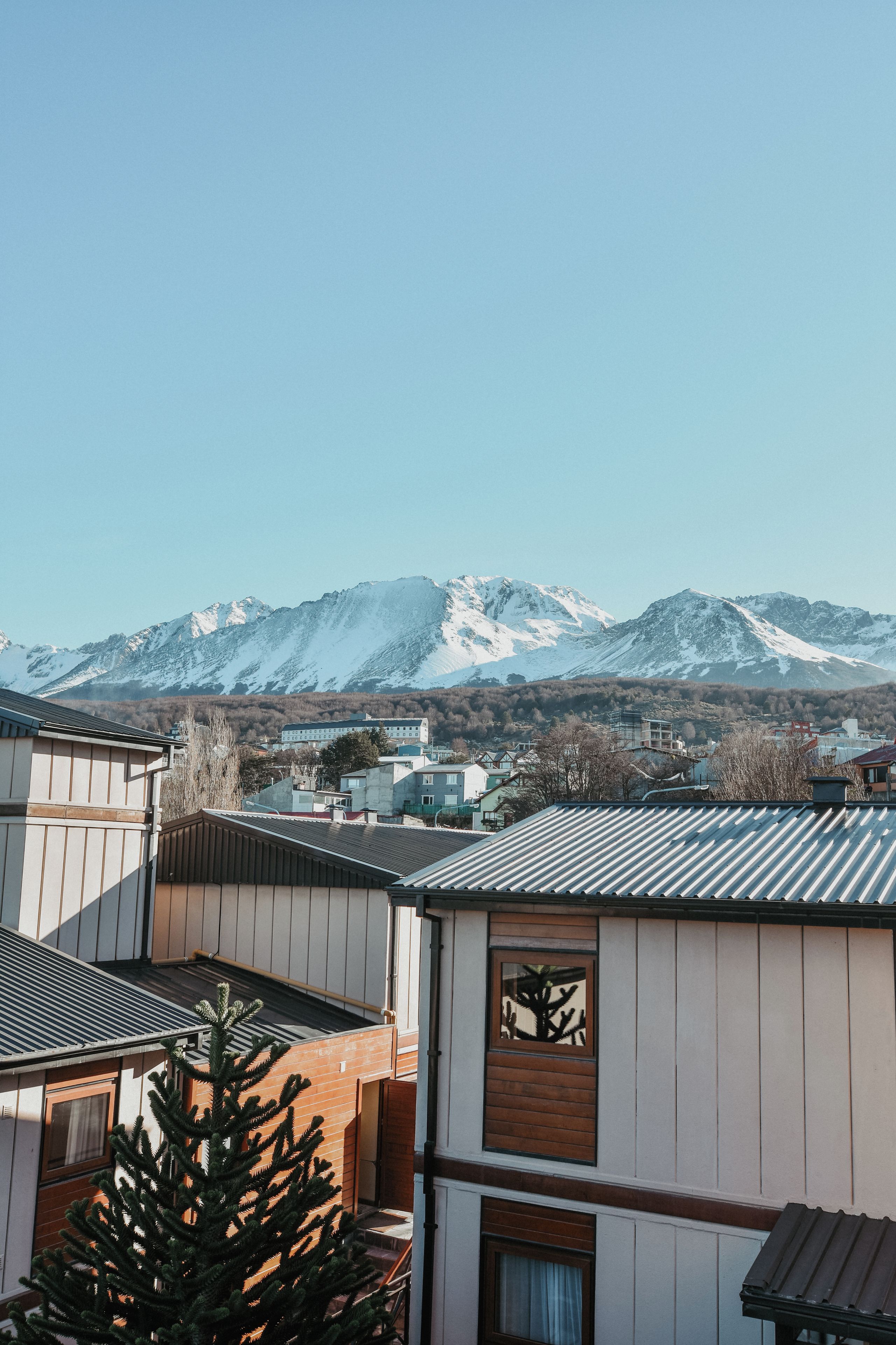 A residential area with houses, a mountain range in the background, and a clear sky.