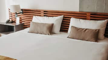 A hotel room with a large bed, wooden headboard, two bedside tables, and three framed pictures on the wall.