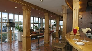 En rummelig lobby med høje lofter, store vinduer og et barområde.