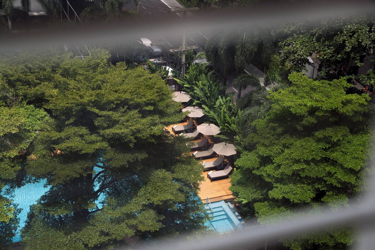 An aerial view of a resort with a pool surrounded by lush greenery and sun loungers.