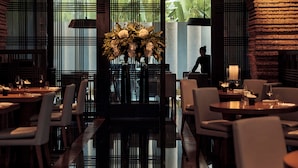 A restaurant with a polished floor, white chairs, and a central floral arrangement. - COMO Metropolitan Bangkok (Bangkok)