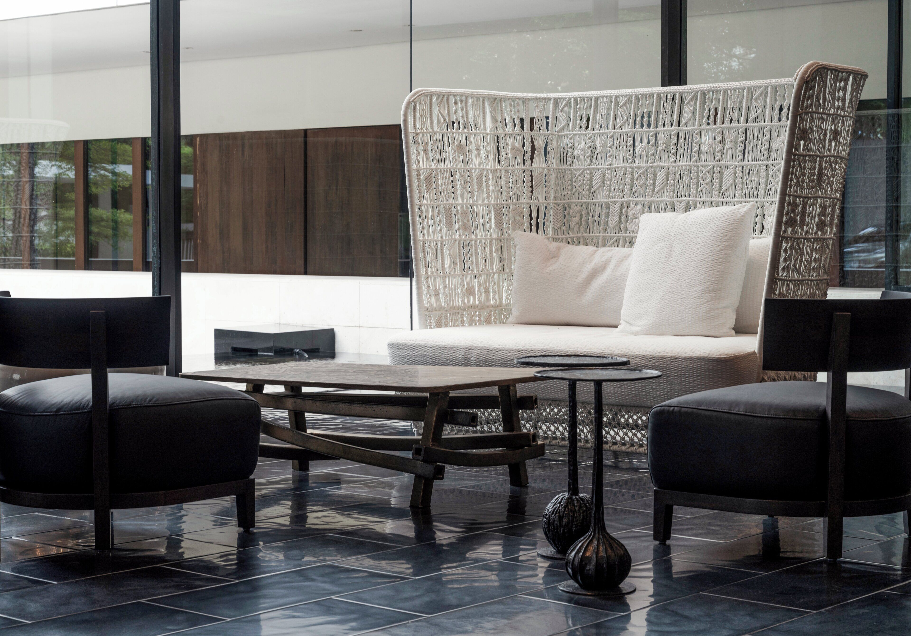 Una sala de estar moderna con un sofá, dos sillones, una mesita de centro y un jarrón decorativo.