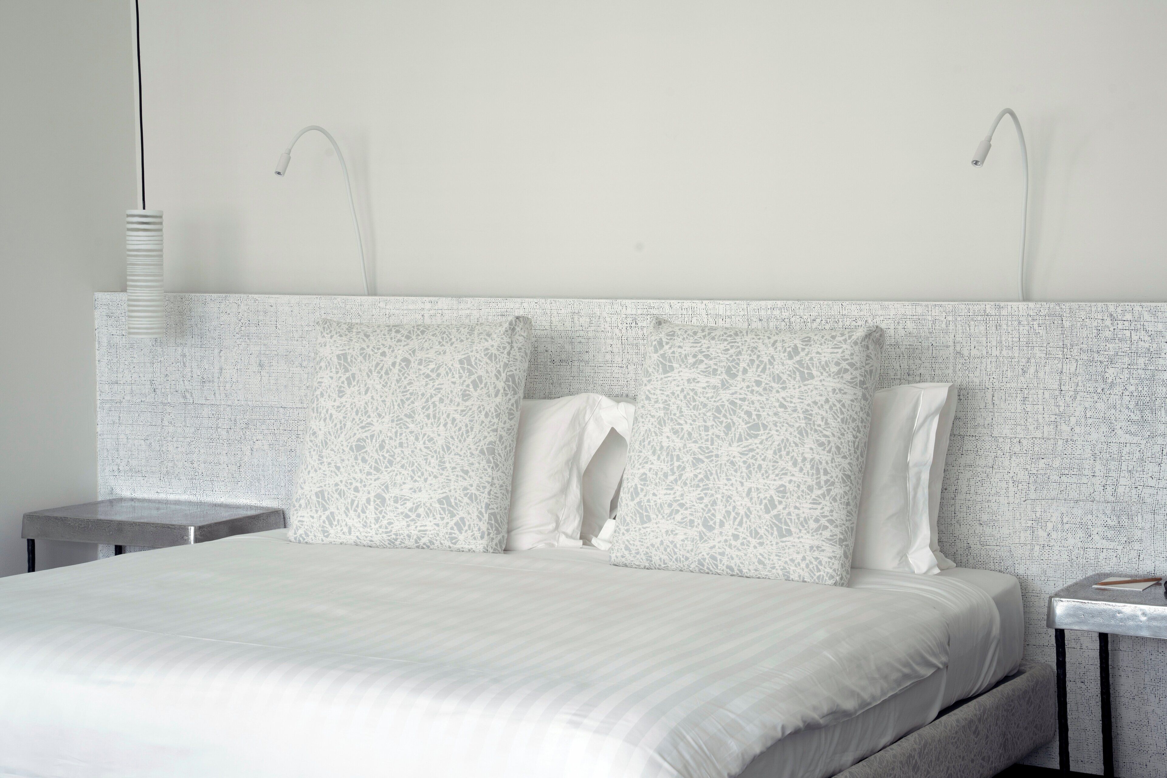 A modern bedroom with a large bed, two bedside tables, and a patterned headboard.