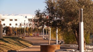 An outdoor area with a playground, trees, and a building in the background. - Hotel Corona de Atarfe (Atarfe)