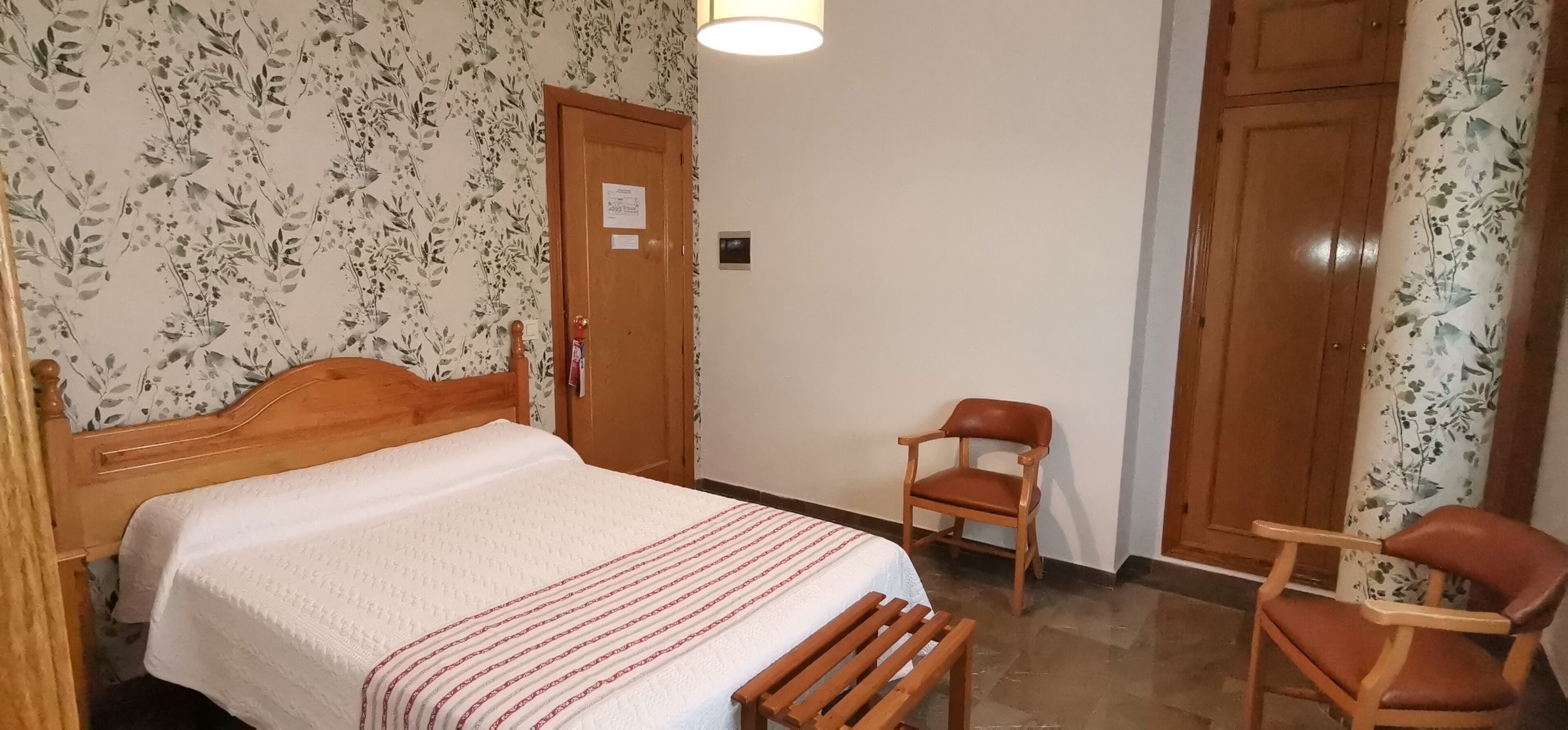 Ein Schlafzimmer mit einem hölzernen Bett, einem Sessel und einer Tür.