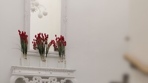 A staircase with a white console table holding red flowers and a mirror. - Hotel Corona de Atarfe (Atarfe)