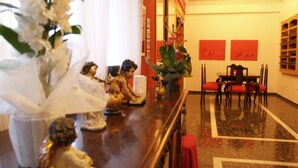 A hotel lobby with a reception desk, a dining area with red chairs, and a large vase with flowers. - Hotel Corona de Atarfe (Atarfe)