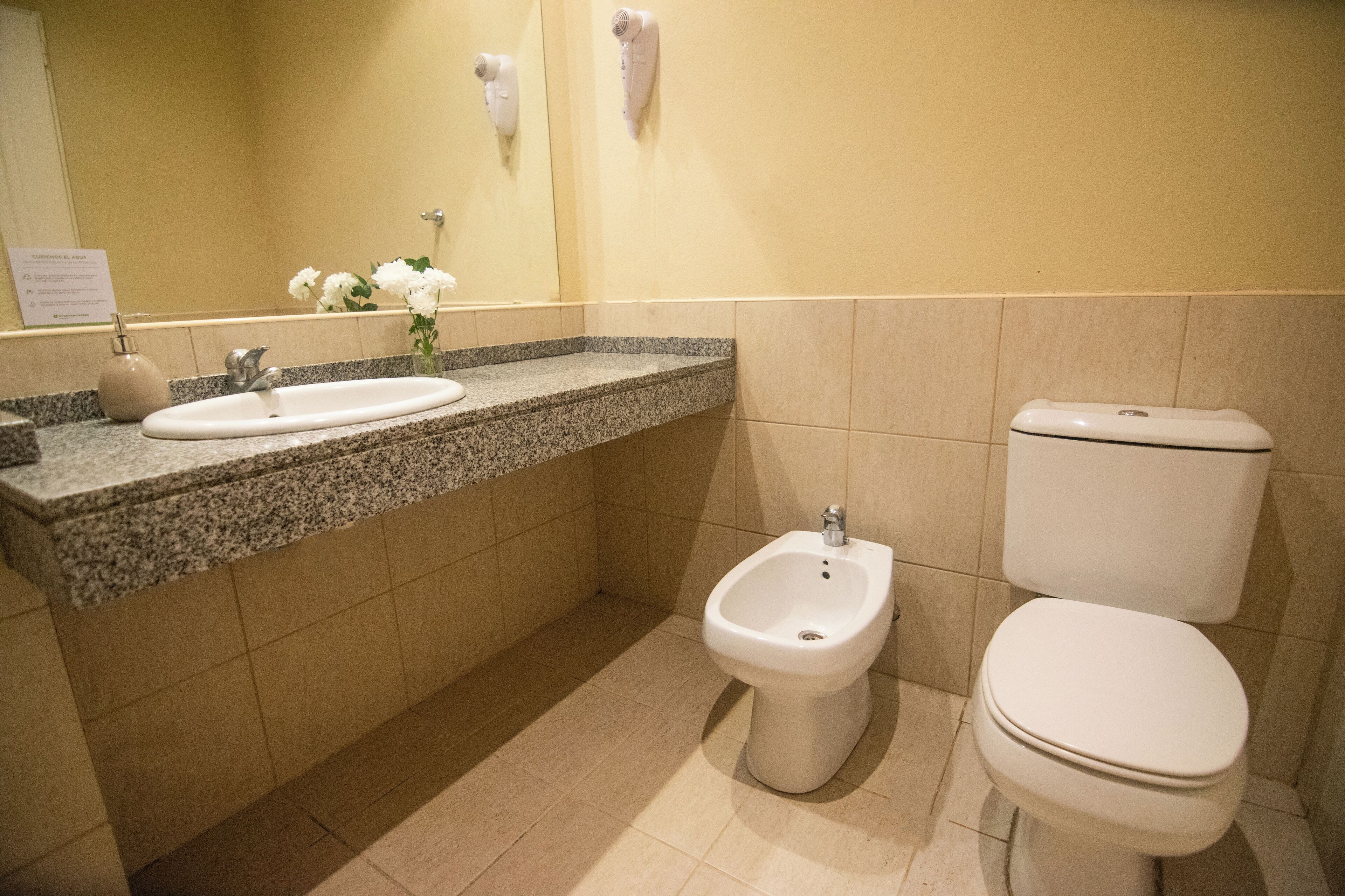 A bathroom with a sink, bidet, and toilet.