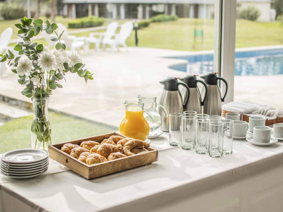 Un buffet de petit-déjeuner avec des croissants, du jus de fruits, des pots de café et des tasses.