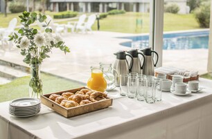 Montaje de un bufé de desayuno con croissants, zumo, cafeteras y tazas.