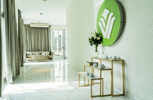 Habitación de hotel moderna con suelo de mármol, sofá, mesa de centro y un letrero verde sujeto a la pared.