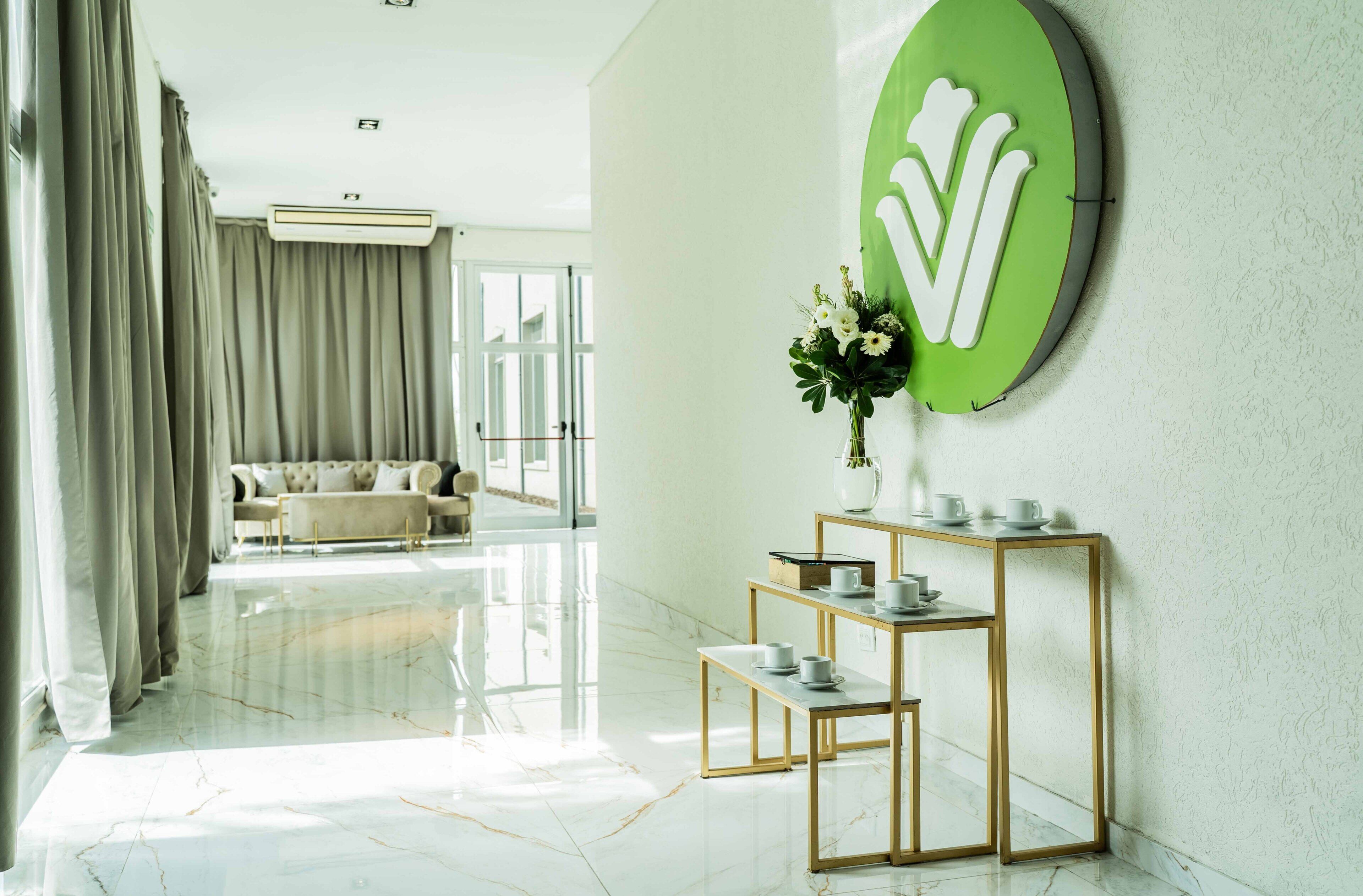 Habitación de hotel moderna con suelo de mármol, sofá, mesa de centro y un letrero verde sujeto a la pared.