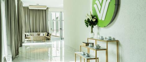 Habitación de hotel moderna con suelo de mármol, sofá, mesa de centro y un letrero verde sujeto a la pared.