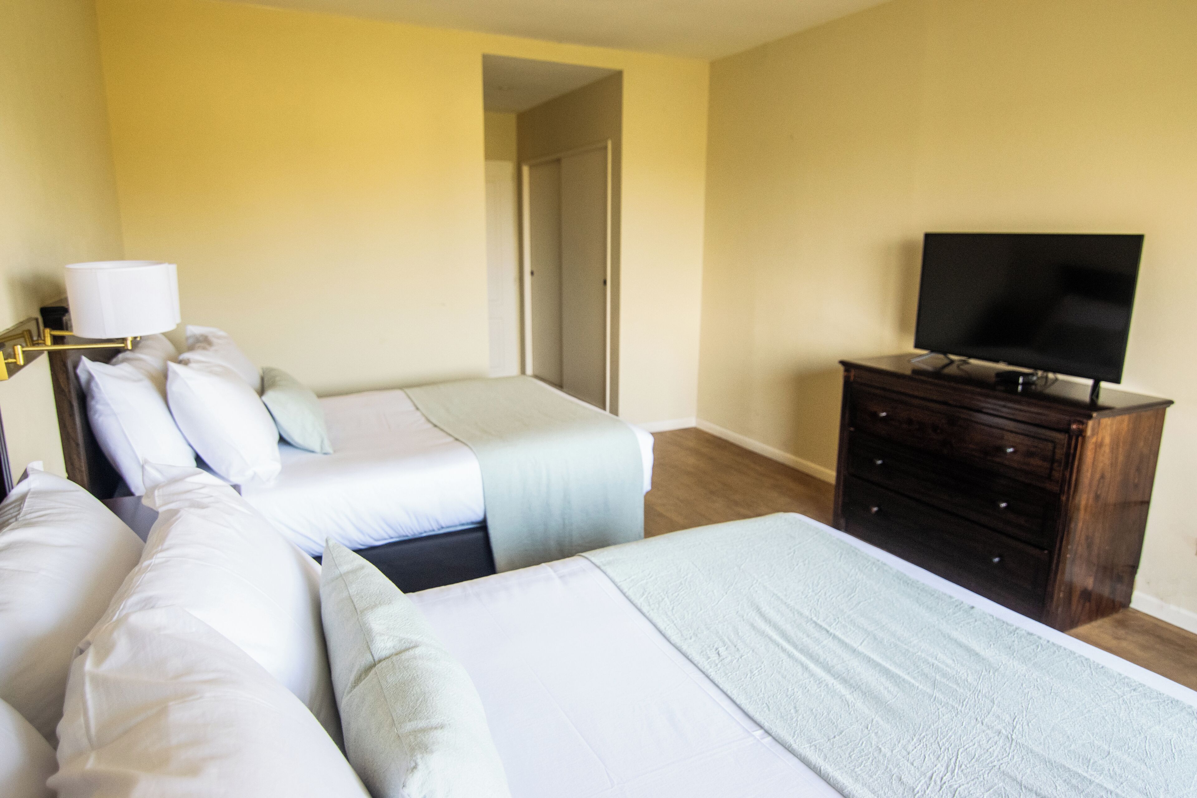 Une chambre d’hôtel avec deux lits, une télévision, une commode et une lampe.