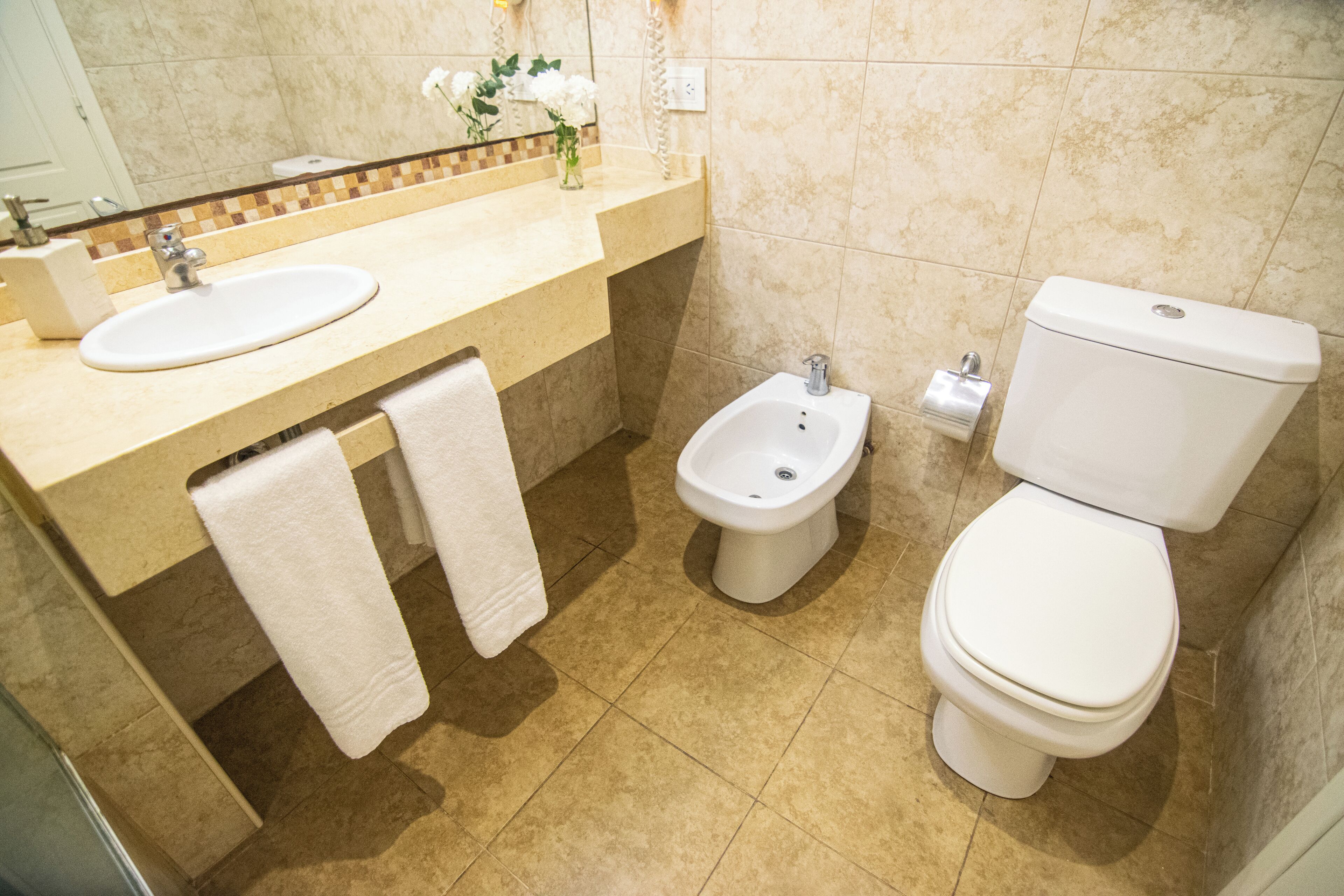 A bathroom with a sink, bidet, and toilet.